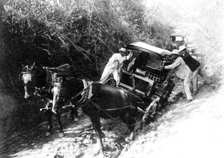 Horse drawn cart stuck in mud and people helping to dislodge it