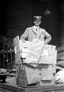 Mail man with a basket full of parcel post packages