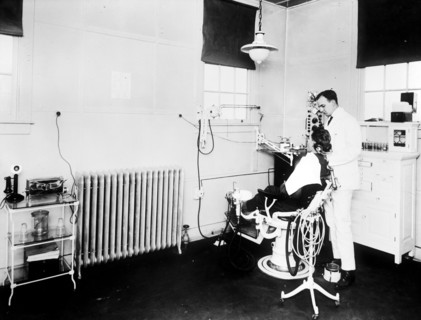 Patient and dentist inside early 1900s dental office.
