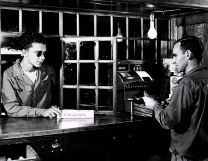 A visually impaired man purchasing a box of cigarettes at a store counter