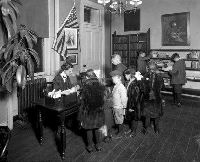Children and librarian in an early 1900s library.