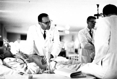 Physician examining a patient at bedside.