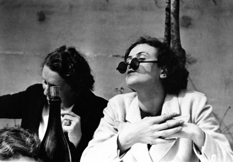 Woman in cafe wearing dark sunglasses with bottle of wine