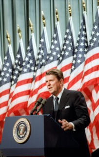 President Reagan speaking in front of American Flags.