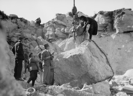 Construction of the Haifa harbour. Workers in the Athlit quarries. Crane raising a huge boulder ca. 1920