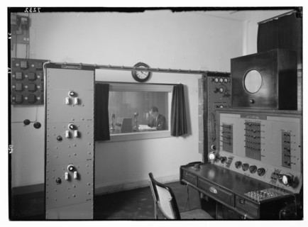 Radio studio. Control room, looking into the studio where an announcer is broadcasting ca. between 1934 and 1939