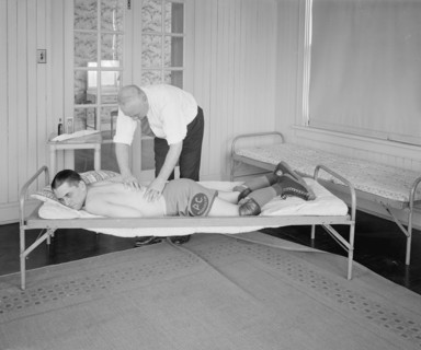 An athlete receiving a rub down by a trainer ca.  between 1910 and 1925