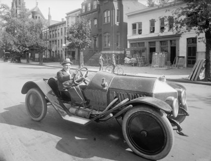 A man driving an early 20th century roadster car ca.  between 1910 and 1926
