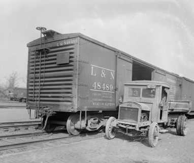 Truck parked next to an empty railroad car (box car) ca.  between 1910 and 1926