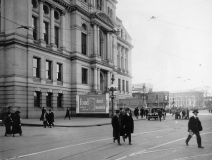 Pedestrians walk by a Food Don't Waste it Billboard donated by Old Colony Advertising Company ca.  between 1910 and 1935