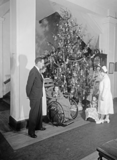 Nurses around Christmas tree with children in wheelchairs ca. between 1910 and 1935