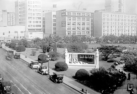 Cars parked in road near a bulletin board donated to U.S. Food Administration by Foster & Kleiser ca.  between 1910 and 1935