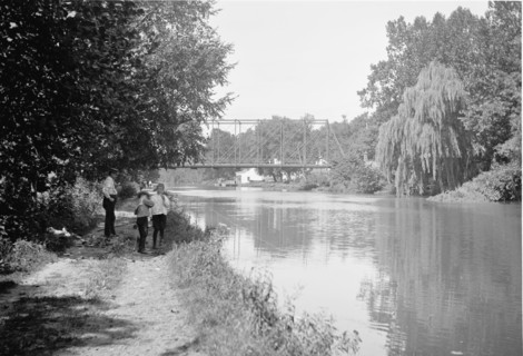 Kids fishing in the C&O canal, the Chain Bridge in the background ca. between 1909 and 1923