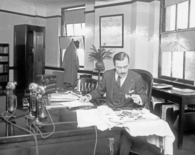 R.G. Cholmeloy-Jones, Director of War Risk Department, eating at his desk ca. between 1909 and 1940