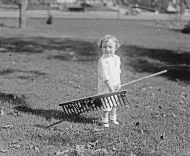 A young toddler girl holding a rake ca.  between 1918 and 1920