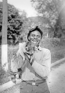 Smiling man holding a racoon  ca.  between 1918 and 1921