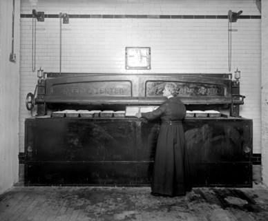 Woman baking, using a commercial oven at the Caking Baking Company group ca.  between 1918 and 1928