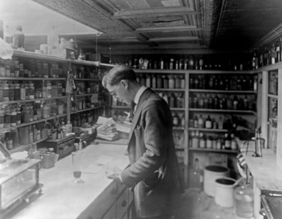 Pharmacist at People's Drug Store, No. 5, 8th and H Streets, N.E., Washington, D.C., looking at prescriptions on the counter ca. between 1909 and 1932