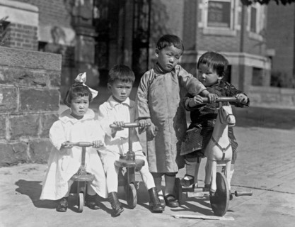 Four children, possibly Chinese, with small tricycles ca. 1909