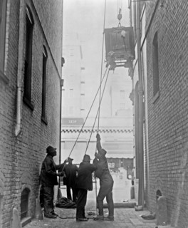 Three African American men lifting a piece of equipment, with block and tackle, at the Standard Engraving Company ca. 1909