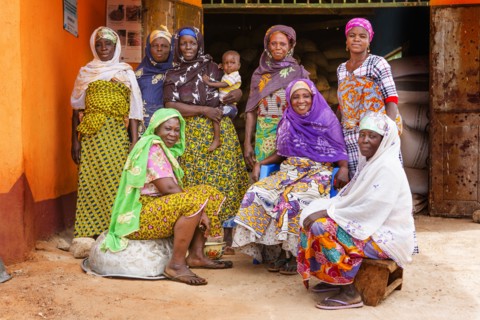 These West African women wearing traditional colorful dress pose for the camera in their village ca. 21 February 2018