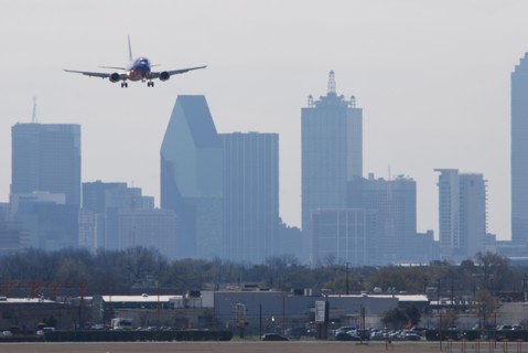 A Southwest Airlines plane landing at Love Field in Dallas, TX; Downtown Dallas in the background (ca. 2010, note the old color scheme)