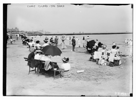 Over-dressed revelers relax on the beach at Coney Island