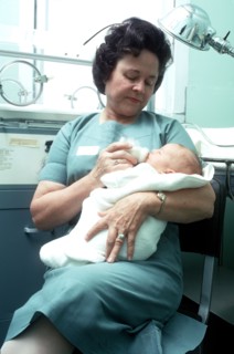 A nurse feeds an infant.
