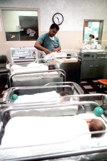 Woman tending to a newborn baby in the infant ward at Womack Army Hospital.