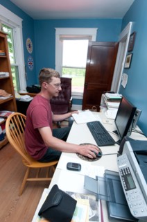 An organic farmer sits at the computer in his office