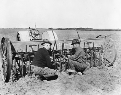 County agent inspecting farmer's wheat seeder