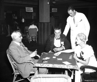 Group of men and and one woman playing cards