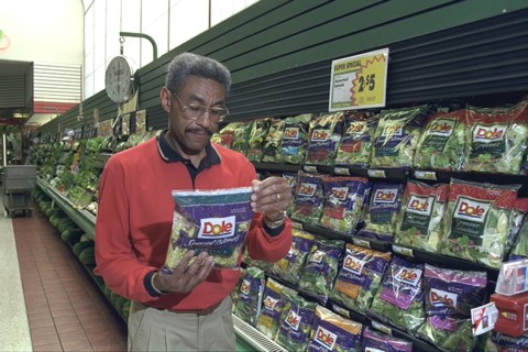 Shopper Looks Over Packaged Lettuce