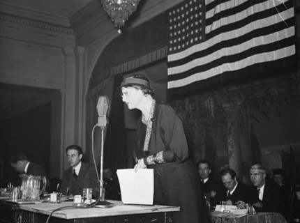 Woman speaking into a microphone at a patriotic event