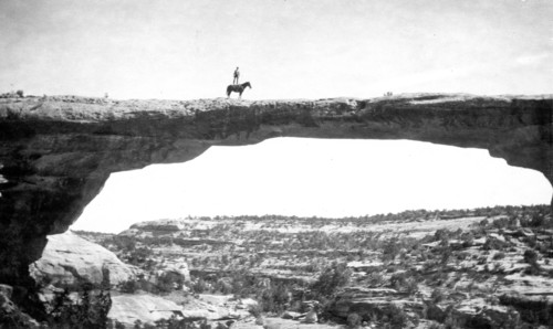 Natural Bridges National Monument in Utah. In this short, we see Dan Perkins (USGS) standing on his horse 'Cap' on top of Owachomo Bridge. ca. 1925