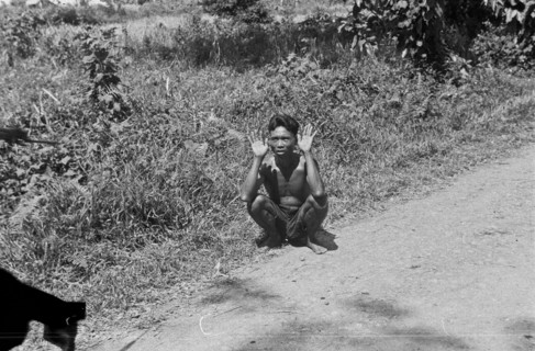 1947 - Medan. Indonesian is squatting with his hands up and makes gesture of surrender - Location: Indonesia, Dutch East Indies