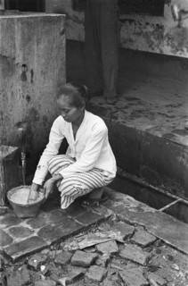 Indonesian woman (baboe?) Busy with a basket at a tap; Date 1947; Location Indonesia, Dutch East Indies