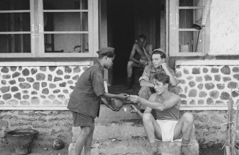 Soldier exchanges a cigarette for a coconut. The young Indonesian wears a kind of uniform. July 21, 1947; Location Bandoeng, Indonesia, Java, Dutch East Indies