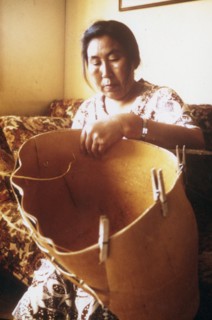 Eskimo woman from the village of Ambler Alaska making traditional birch bark basket for harvesting of berries ca. 1975