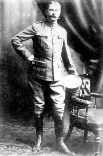 Lord Kitchener, standing by chair, in uniform