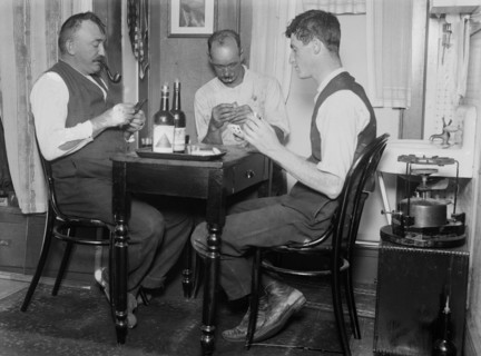 Men playing cards next to a primus stove in a home in Broad Channel, Queens ca. 1910-1915