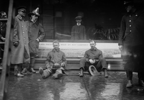 Firemen seated on the sidewalk after fighting a fire in a New York City subway tunnel which took place near West 55th Street and Broadway, January 6, 1915