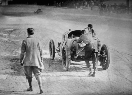 Race car driver Ralph DePalma and his riding mechanic, Rupert Jeffkins, pushing their car towards the finish line at the 1912 Indianapolis 500 automobile race
