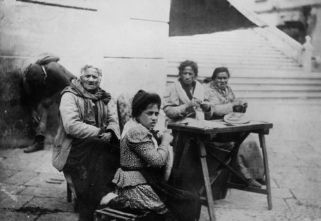 Older man and women sitting at a table in Amalfi Italy, possibly at the bottom of the steps leading to the Amalfi Duomo ca. 1910-1915