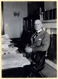 Miles Poindexter, three-quarter length portrait, seated at desk, facing left ca. 1920-1932