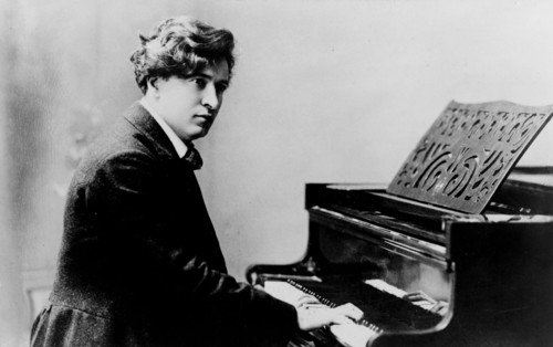 Postcard showing Ferruccio Busoni, half-length portrait, seated at piano, facing right. 1890-1900