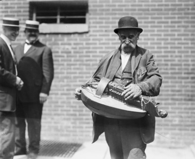 A street musician playing a hurdy-gurdy ca. 1910-1915