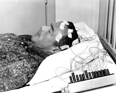(1962) Mercury astronaut M. Scott Carpenter lies on a bed with biosensors attached to his head during astronaut training activities at Cape Canaveral