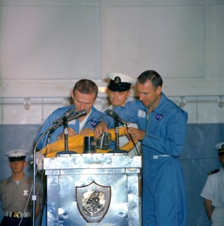 (18 Dec. 1965) Astronauts Frank Borman (left), Gemini-7 command pilot, and James A. Lovell Jr., pilot, take time out during their welcoming ceremonies aboard the aircraft carrier USS Wasp to autograph...