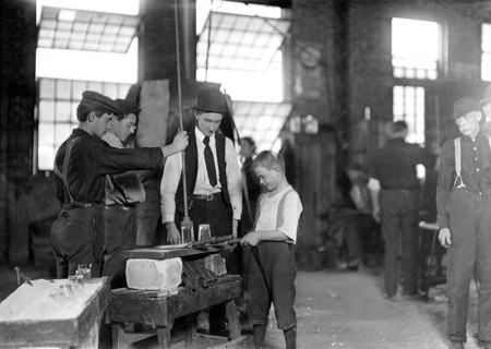 Teaching the young idea. The boss (who began at 10 years of age, and has been at it for 30 years) showing a beginner (who is apparently 9 or 10), October 1908